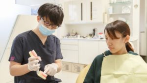 NSデンタルオフィスの院長の鈴木宏尚が患者さんに説明している様子