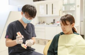 NSデンタルオフィスの院長の鈴木宏尚が患者さんに説明している様子